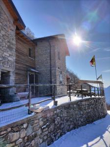 a building with a stone wall and a flag at Le Casette di Laila in Colonno