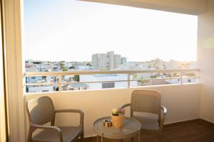 einen Balkon mit 2 Stühlen, einem Tisch und einem Fenster in der Unterkunft Glamorous, Renovated 3-Bedroom Apt in Nicosia in Nikosia