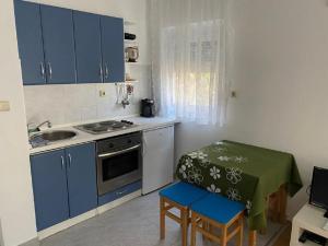 a kitchen with blue cabinets and a table and a sink at Apartments Olea in Rab