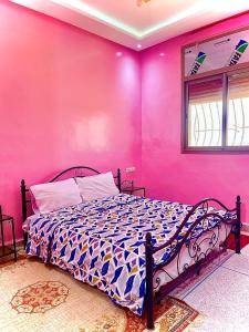 um quarto com uma parede cor-de-rosa e uma cama. em Résidence Othmane em Dakhla