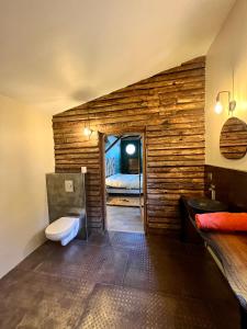 a bathroom with a wooden wall with a toilet and a bed at La cabane de babarot in Aups