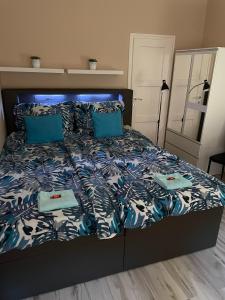 Cama con sábanas y almohadas azules y blancas en CentRoom Apartman, en Sátoraljaújhely