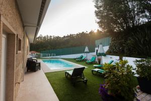 a backyard with a swimming pool and chairs and grass at Casa Serra dos Picos - Casa de Ferias, Braga in Braga