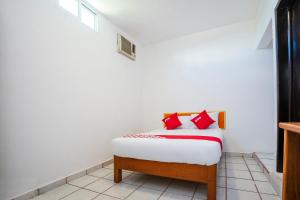 a bedroom with a bed with red pillows on it at OYO Hotel Mexico in Chetumal