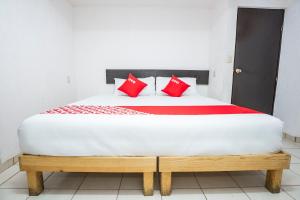 a bedroom with a bed with red pillows on it at OYO Hotel Mexico in Chetumal