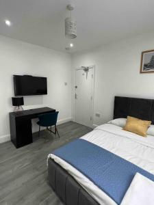 a bedroom with a bed and a desk and a television at Inviting 2-Bed Apartment in Ilford in Ilford