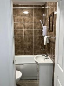 a bathroom with a tub and a sink and a toilet at Inviting 2-Bed Apartment in Ilford in Ilford