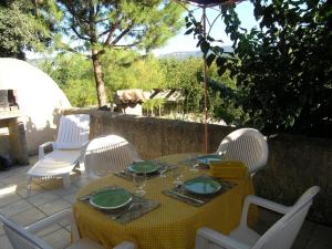 mesa con sillas blancas y mantel amarillo en La Bastide de la Peyrolière avec piscine et tennis face au Luberon, en Apt