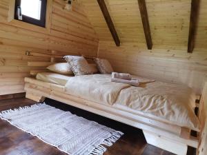 a bed in a log cabin with wooden walls at Cazare la Vama Buzăului - Căsuța Festung in Crivina