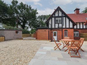 a patio with two chairs and a table in front of a house at 2 Golf Links Cottages in Northwich