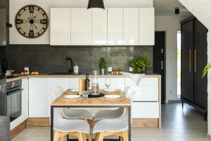 a kitchen with a wooden table and white cabinets at Domek Zielony Zakątek in Słajszewo