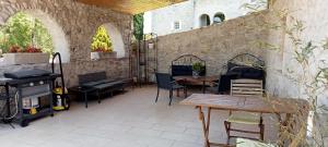 eine Terrasse mit Tischen und Stühlen und einer Steinmauer in der Unterkunft La Dame Blanche in Saint-Maurice-dʼIbie