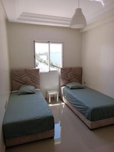 a bedroom with two beds and a window at Résidence calme avec piscine Plage à 5min in Mohammedia