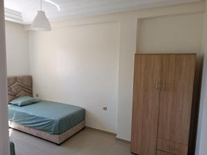 a bedroom with a bed and a wooden cabinet at Appartement avec piscine à Mohammedia Plage à 5min in Mohammedia