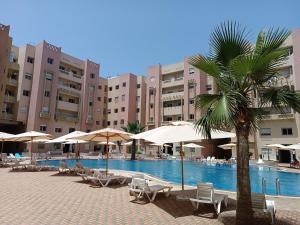 a resort with a swimming pool with chairs and umbrellas at Appartement avec piscine à Mohammedia Plage à 5min in Mohammedia