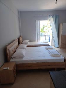 two beds in a room with a window at Ionian View Guest House in Qeparo