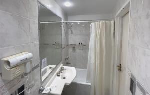 a white bathroom with a sink and a shower at Hotel HR Plaza Luxor in Buenos Aires