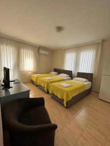 two beds in a room with a couch and a television at Cicek Apart Hotel in Cesme