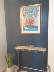 a painting on a blue wall next to a table at Dafne Home in Pompei