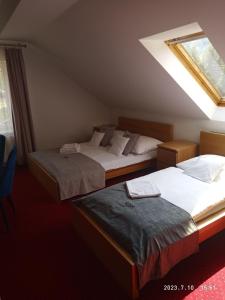 two beds in a hotel room with a skylight at Lusia in Wisła