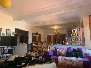 salon z fioletową kanapą i telewizorem w obiekcie the colombiana villa w mieście Souira Guedima