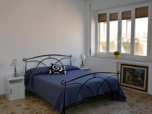 - une chambre avec un lit bleu et 2 fenêtres dans l'établissement All That Sicily ORTIGIA, à Syracuse