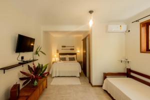 a room with a bedroom with a bed and a tv at Ilhabela Studios in Ilhabela