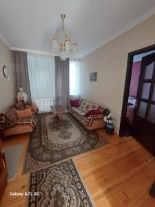 sala de estar con lámpara de araña y alfombra grande en guest house lela rezo, en Kazbegi