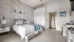 a bedroom with a white bed and a wall at Blue's Guest House - East London Bonza Bay in East London