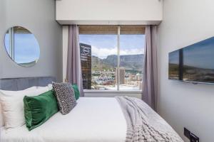 ケープタウンにあるStylish Studio Apartmentのベッドと大きな窓のある寝室
