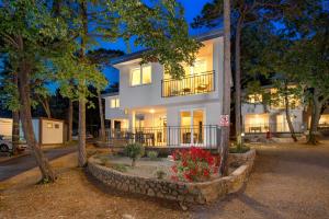 een groot wit huis met bomen en bloemen bij Holiday Homes Oštro in Kraljevica