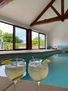 two glasses of white wine next to a swimming pool at La Clé des Champs in Jodoigne