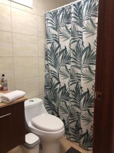 y baño con aseo y cortina de ducha en blanco y negro. en Elegante suite amoblada - Park La Carolina cerca Hotel Dann Carlton, en Quito