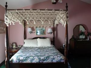 a bedroom with a canopy bed and pink walls at Woodstock Inn, Station and Brewery in North Woodstock