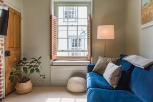 a living room with a blue couch and a window at Coop's Landing - Charming seaside bolthole in Deal
