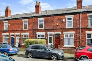 a red brick house with cars parked in front of it at Friendly Stockport in Stockport