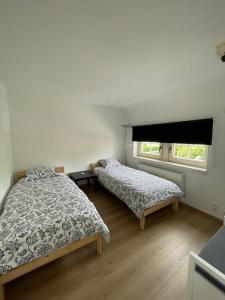 Jodoigne的住宿－La Clé des Champs，一间卧室设有两张床和窗户。