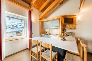 kuchnia ze stołem i krzesłami oraz oknem w obiekcie Residence Nevegall w Livigno