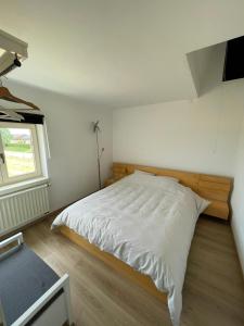 1 dormitorio con 1 cama blanca grande y ventana en La Clé des Champs, en Jodoigne