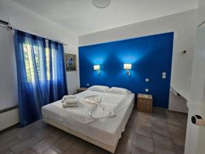 una camera da letto con un letto grande con una parete blu di Corfu Glyfada Beach Apartments a Glifada (Glyfada)