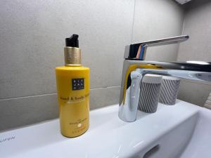 a yellow bottle of soap sitting on top of a sink at Stay Swiss 1 bedroom apartments in old town in Porrentruy