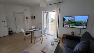 Una sala de estar con una mesa y un televisor en la pared. en Villa Alex, en Tavronitis