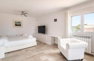 a white bedroom with a bed and a chair at Villa Can Bellmunt in La Aranjasa