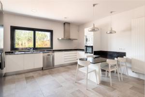 a kitchen with white cabinets and a table and chairs at Villa Can Bellmunt in La Aranjasa