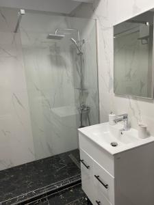 uma casa de banho branca com um lavatório e um chuveiro em Eric Apartment em Mamaia Nord – Năvodari