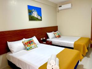 una habitación de hotel con 2 camas y una foto de un castillo en Hostal Quil, en Guayaquil