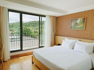 a bedroom with a large bed and a large window at Rosie Balcony Hotel Phu Quoc in Phu Quoc