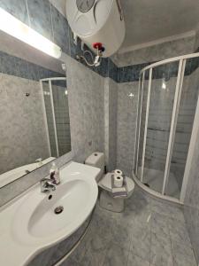 ein Badezimmer mit einem Waschbecken, einem WC und einem Spiegel in der Unterkunft Corfu Glyfada Beach Apartment 45 in Glyfada