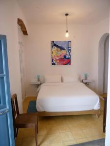 a bedroom with a white bed and a chair at Casa 3 Guesthouse and Artist Residence in Polopos