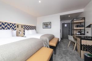 a hotel room with two beds and a desk at Sandman Signature Glasgow Hotel in Glasgow